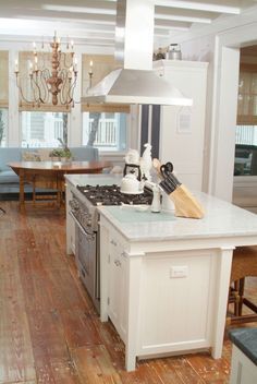 a kitchen with an island, stove top and dining room table in the back ground