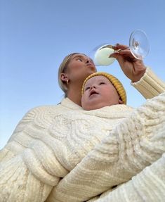 a woman holding a glass of wine next to a baby