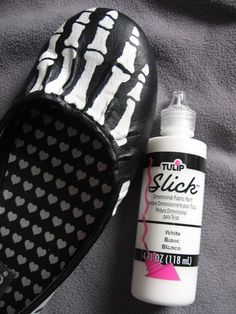 a pair of black and white shoes next to a bottle of glue on a bed