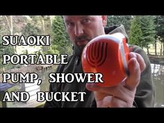 a man holding a red blow dryer in his right hand with the words suaoki portable pump, shower and bucket