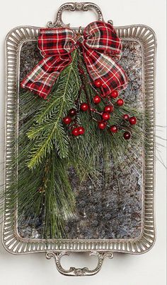 a christmas ornament hanging on the side of a wall with holly and berries