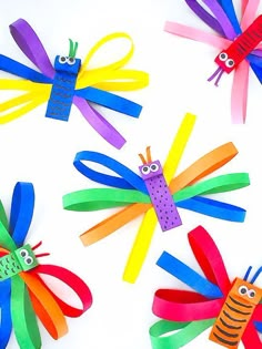 four colorful paper bugs with eyes and antennaes on them, all made out of strips of colored construction paper