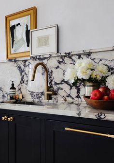 a kitchen with marble counter tops and gold faucet, white flowers on the sink