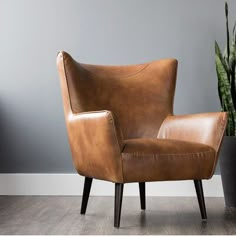 a brown leather chair next to a potted plant