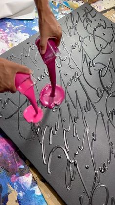 a person is using pink shoes to decorate a piece of art on a table top