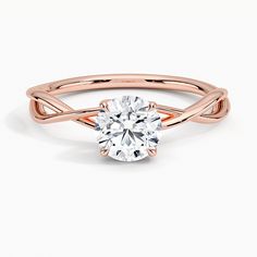 a rose gold engagement ring with an oval cut diamond in the center and twisted band