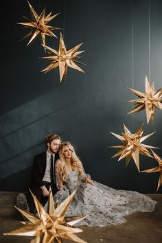 a man and woman sitting next to each other under golden stars