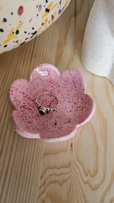 a pink flower shaped dish sitting on top of a wooden table next to a white vase