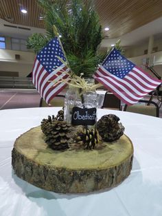 a pine cone centerpiece with an american flag in the background on top of a table