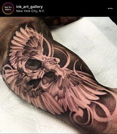 a man's arm with a skull and wings tattoo design on the left shoulder