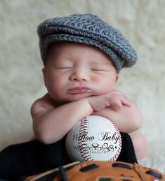 a baby is holding a baseball and wearing a hat