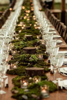 the long table is covered with moss and lit candles