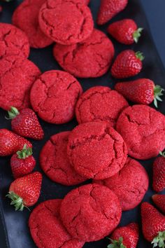 red cookies and strawberries on a black tray