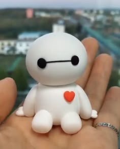 a small white toy sitting on top of someone's hand with a city in the background