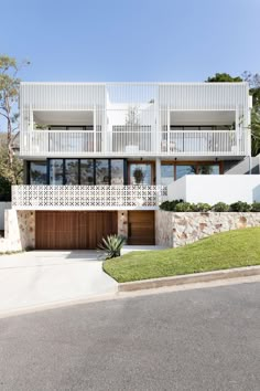 a modern house with white balconies and wooden garages on the front lawn