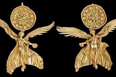 two gold earrings with angel wings and flowers in the center on a black background photo