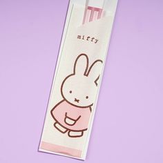 a bookmark with an image of a rabbit on it's back and the words miffy written in pink