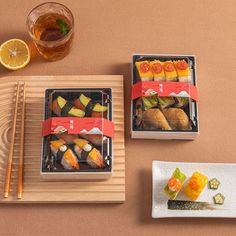 sushi and chopsticks on a wooden tray next to a glass of tea