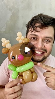 a man pointing to a brown and green teddy bear that is in the shape of a deer