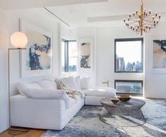 a living room filled with white furniture and a chandelier hanging from the ceiling