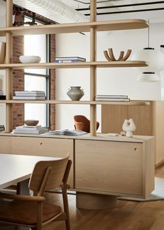 a table with chairs and bookshelves in front of a wall filled with shelves