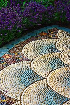 an artistic mosaic design on the ground in front of purple flowers