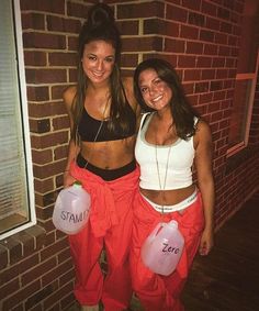 two young women standing next to each other in front of a brick wall holding balloons