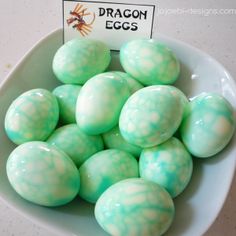 a bowl filled with green and white eggs on top of a marble countertop next to a sign that says dragon eggs