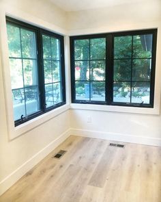 an empty room with two windows and hard wood flooring on the side of it