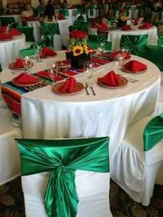 the table is set with green and white linens, red napkins, and sunflowers