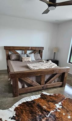 a bedroom with a bed made out of wooden planks and cow hide rug on the floor