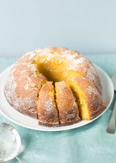 a bundt cake with powdered sugar on top sits on a plate next to a spoon