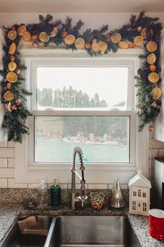 a kitchen sink sitting under a window covered in christmas decorations