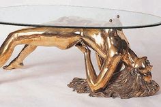 a table with a glass top that has a gold colored animal on it and is shaped like a human figure