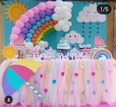 a table topped with an umbrella next to a rainbow cake and cupcakes on top of it