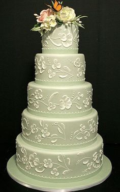 a three tiered wedding cake with white flowers on the top and green frosting