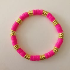 a pink and gold beaded bracelet on a white surface