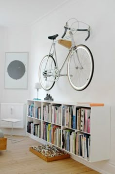 a bicycle mounted to the wall above a bookcase