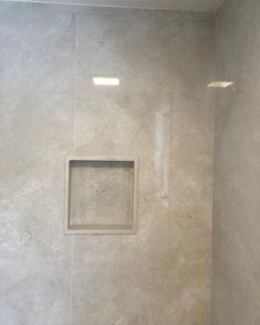 a white tiled shower with a square window in the wall and no curtain on it