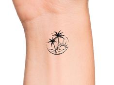 a small palm tree tattoo on the left side of the wrist is shown in black ink