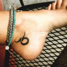 a woman's foot with a tattoo that has an omen symbol on it