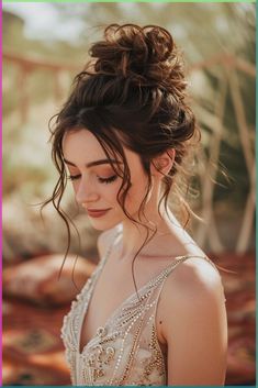 a woman in a wedding dress looking down with her hair pulled back into a bun