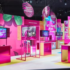 an exhibit with pink walls and colorful displays on the wall, including televisions that are brightly colored