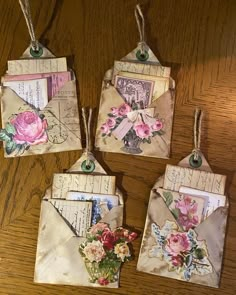 four small envelopes with flowers on them are hanging from twine string and have tags attached to them