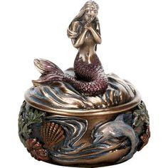 a statue of a mermaid sitting on top of a fish bowl with shells around it