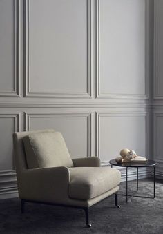 a chair and table in front of a wall with white paneling on the walls