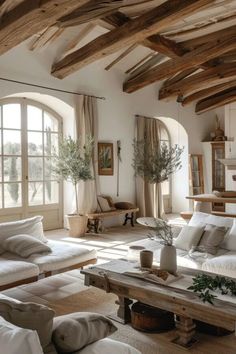 a living room filled with lots of white furniture and wooden beams on the ceiling,