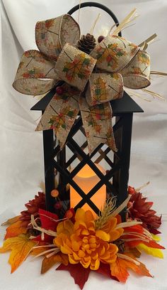 a lantern with a bow on it and some leaves