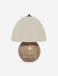 a table lamp with a white shade on top of it and a light brown base