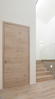 a wooden door sitting next to a set of stairs in a room with white walls